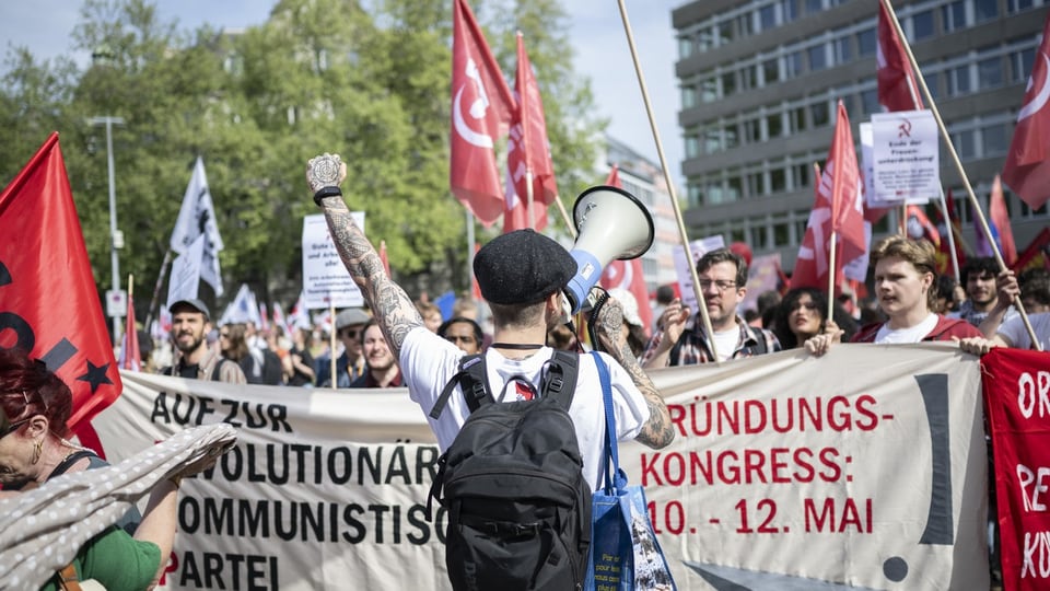 Demonstranten mit Flaggen und Transparenten bei einer politischen Kundgebung.