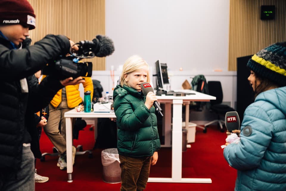 Kinder mit Mikrofonen und Kamera im Studio.