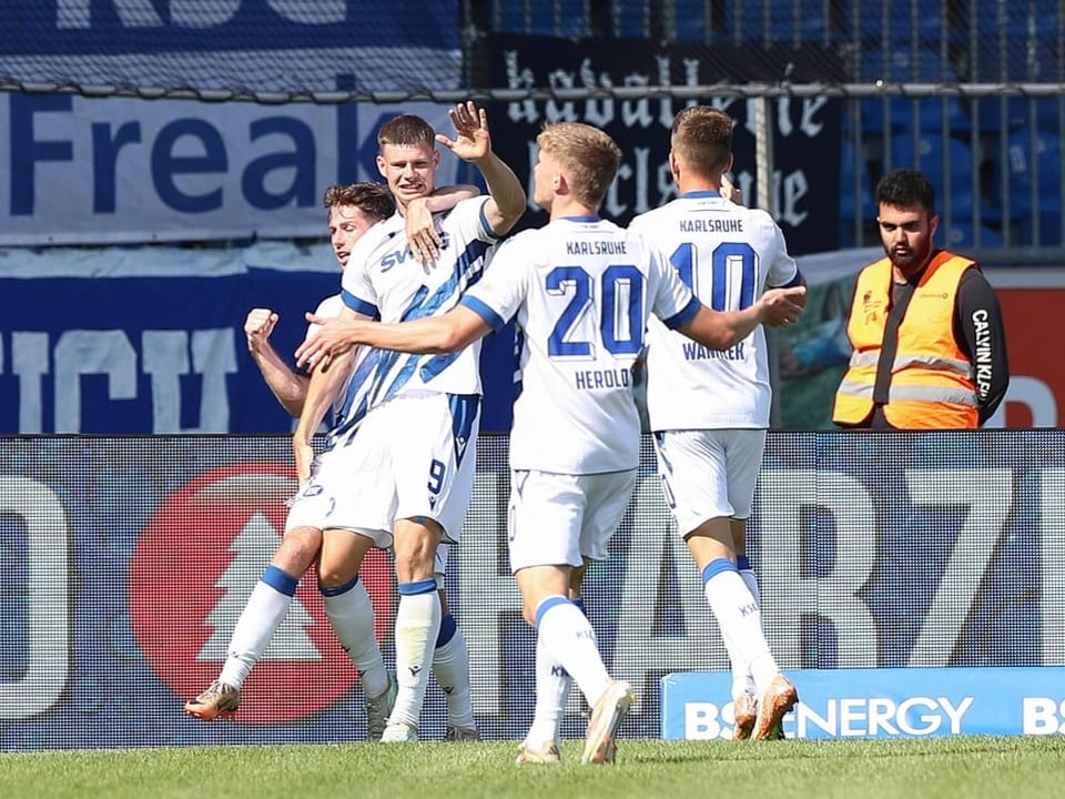 Fussballspieler feiern ein Tor auf dem Spielfeld.