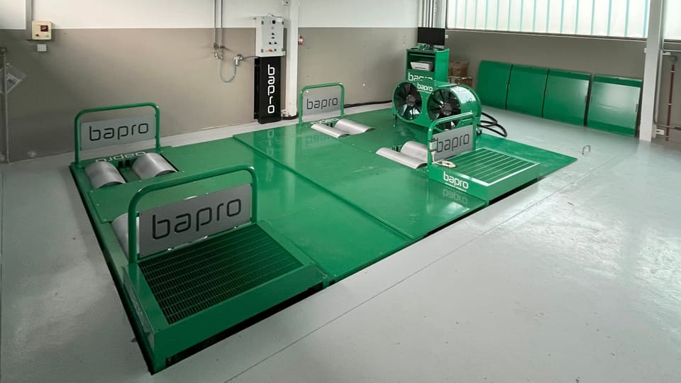 Eine grüne Plattform mit silbernen Rollen in einer Garage. 