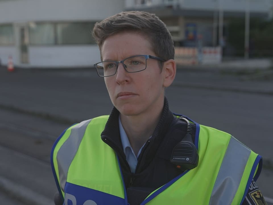 Person in Polizeiweste mit ernster Miene.