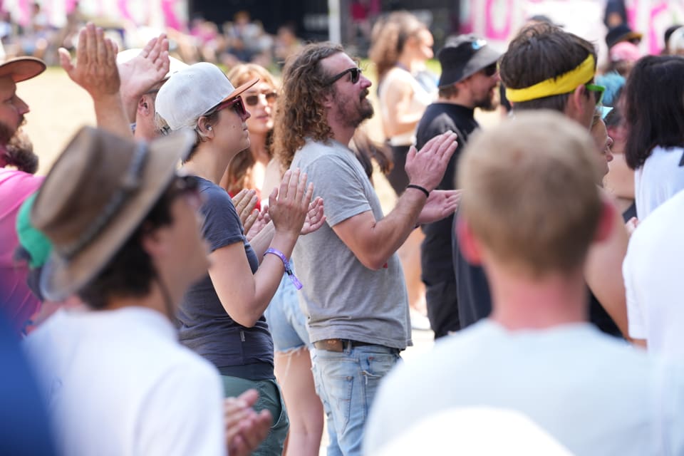 Menschen beim Freiluft-Konzert klatschen am Open Air Lumnezia 2024 in Degen.