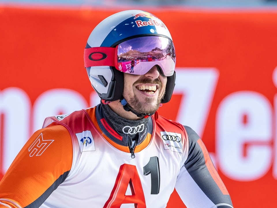 Skifahrer mit Helm und Brille lächelnd im Wettkampf.