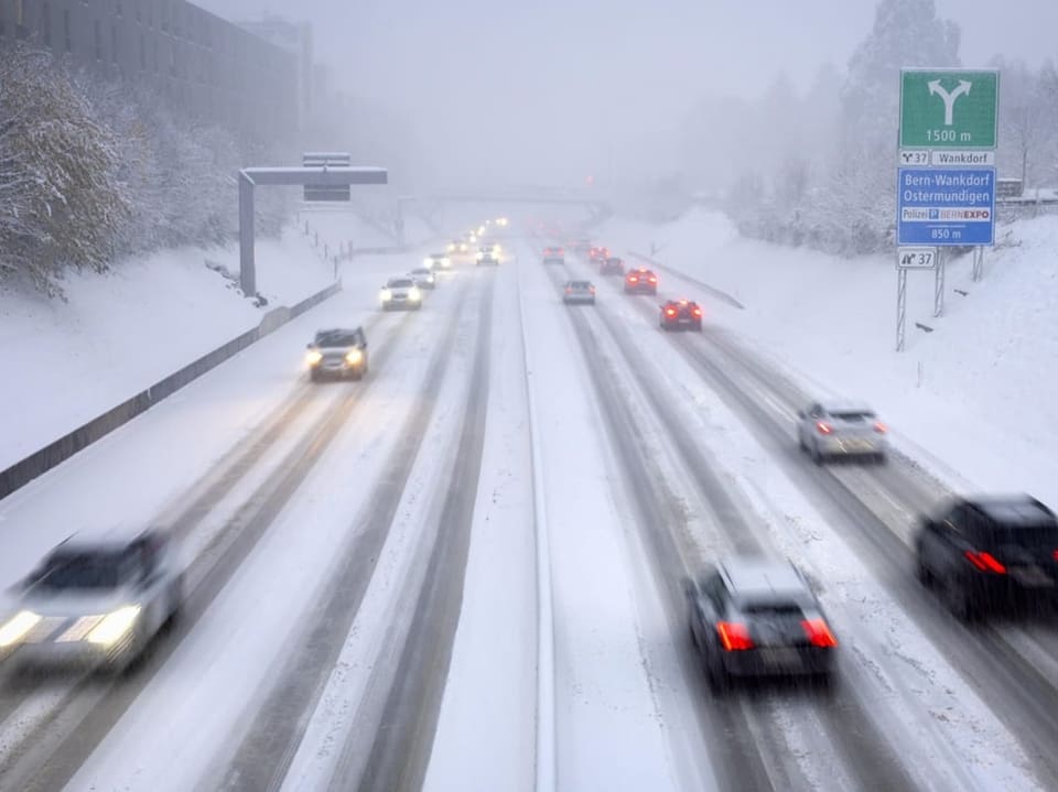 Verschneite Autobahn mit fahrenden Autos.