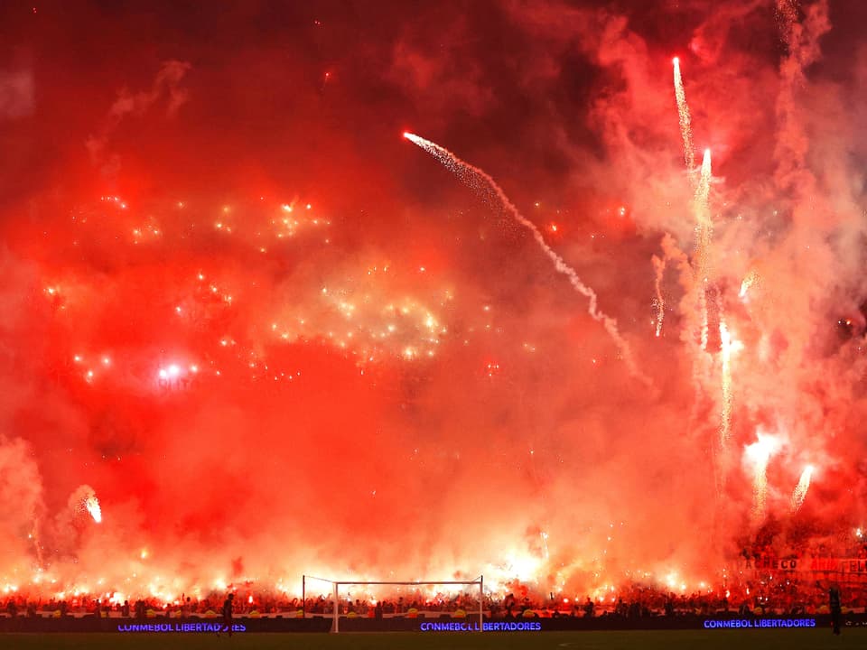 Brennende Pyrotechnik und Feuerwerk in einem Stadion.