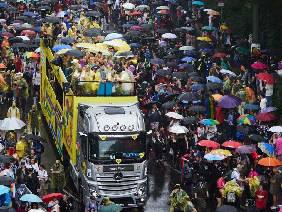 Wagen, Feiernde und zahlreiche bunte Regenschirme.