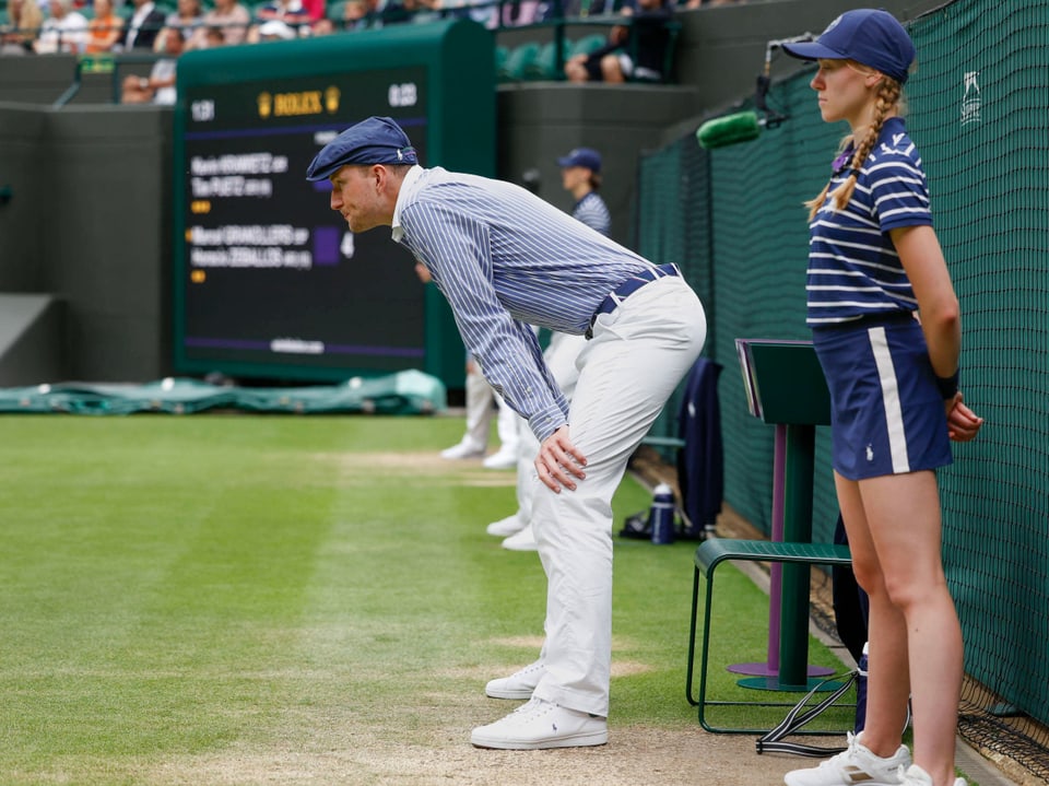 Zwei Linienrichter stehen während eines Tennis-Matchs am Spielfeldrand.