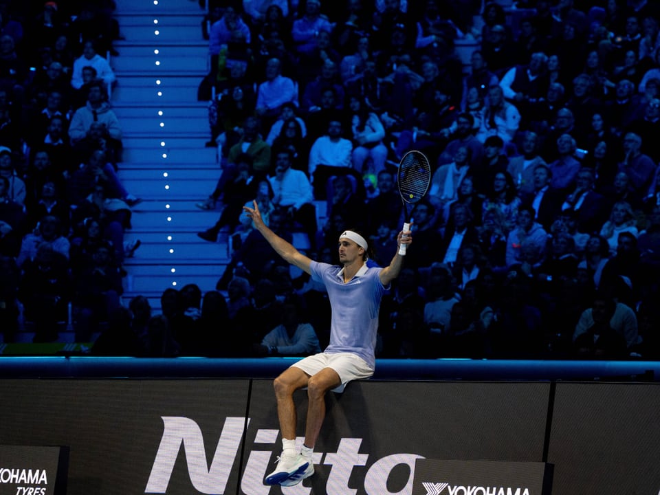 Zverev setzt sich lässig auf die Bande.