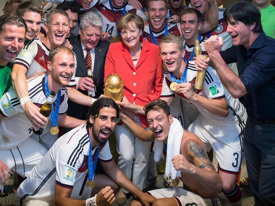 Deutsche Fussballnationalmannschaft mit WM-Pokal und Merkel sowie Gauck.