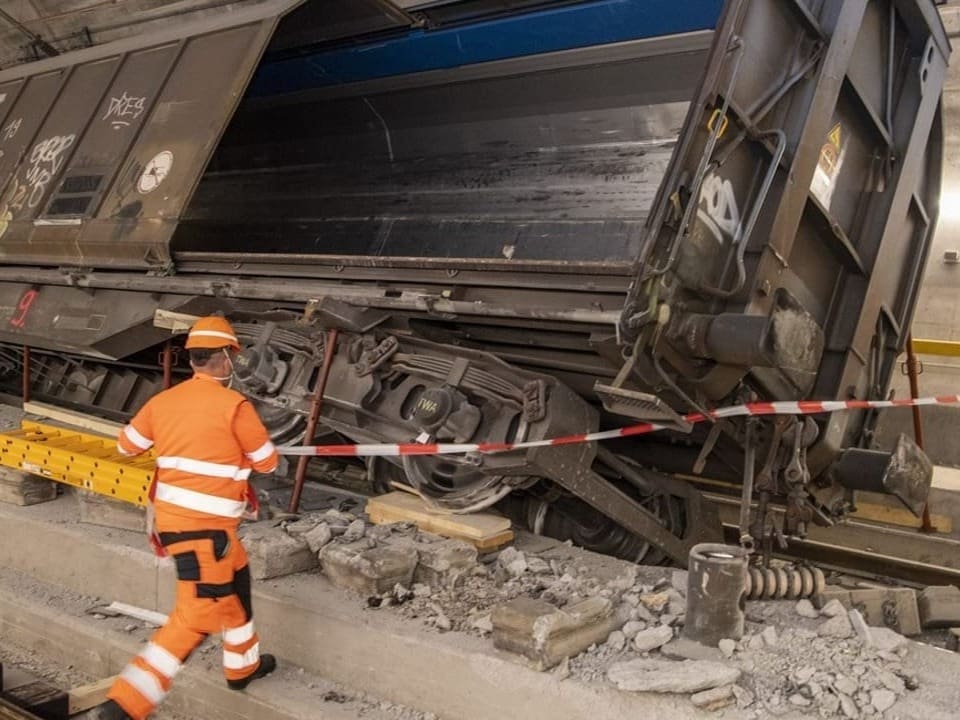 Arbeiter untersucht entgleisten Güterwagen in einem Tunnel.