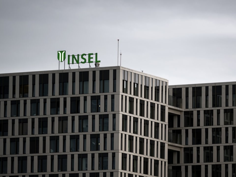 Modernes Gebäude mit dem grünen Schriftzug 'INSEL' vor bewölktem Himmel.