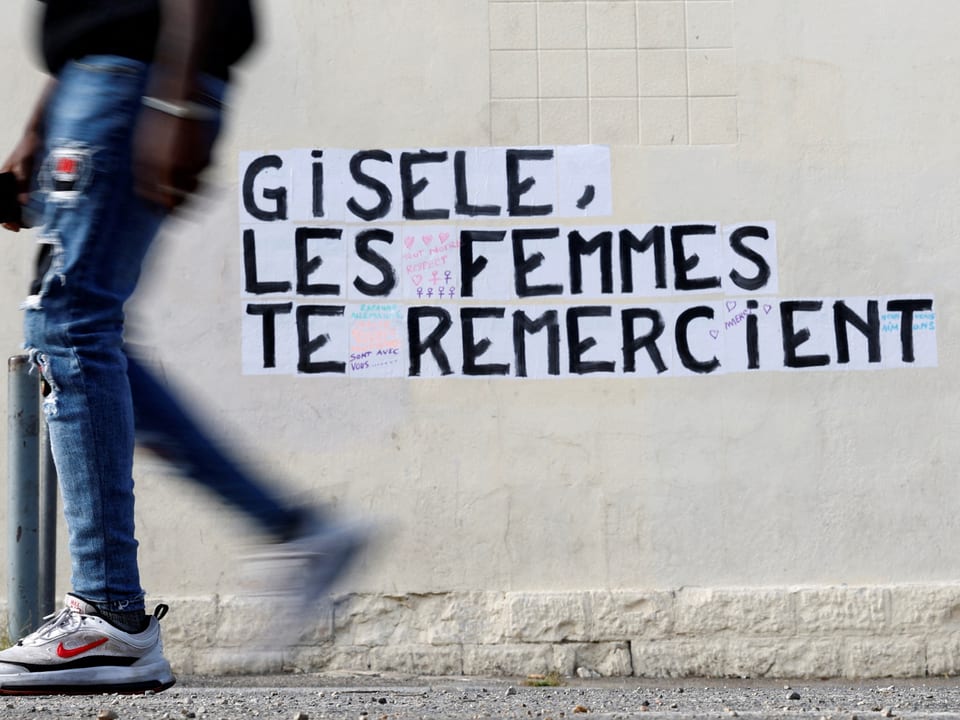 Person vor Wand mit Schriftzug 'Gisele, les femmes te remercient'.