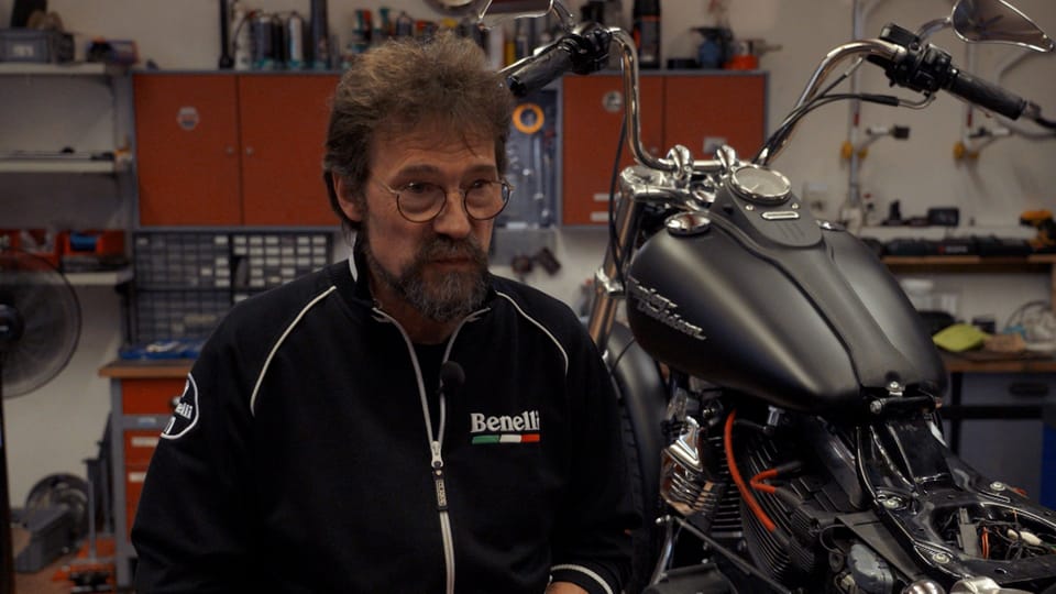 Der Motorradmechaniker Stefan Boss steht in seiner Werkstatt vor einem Motorrad.