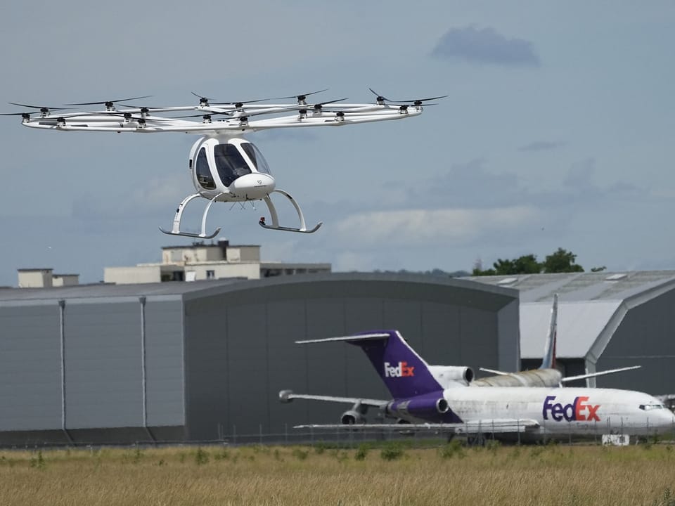 Fliegende Drohne und FedEx-Flugzeug vor Hangars.