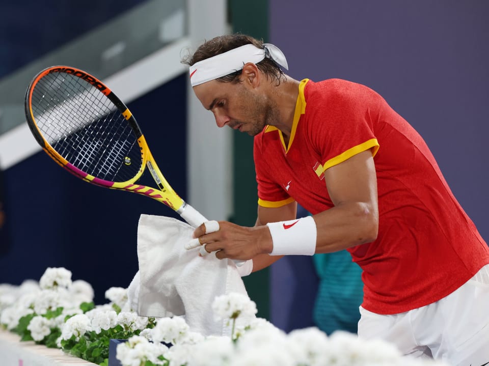 Tennisspieler wischt Schweiss mit Handtuch ab.