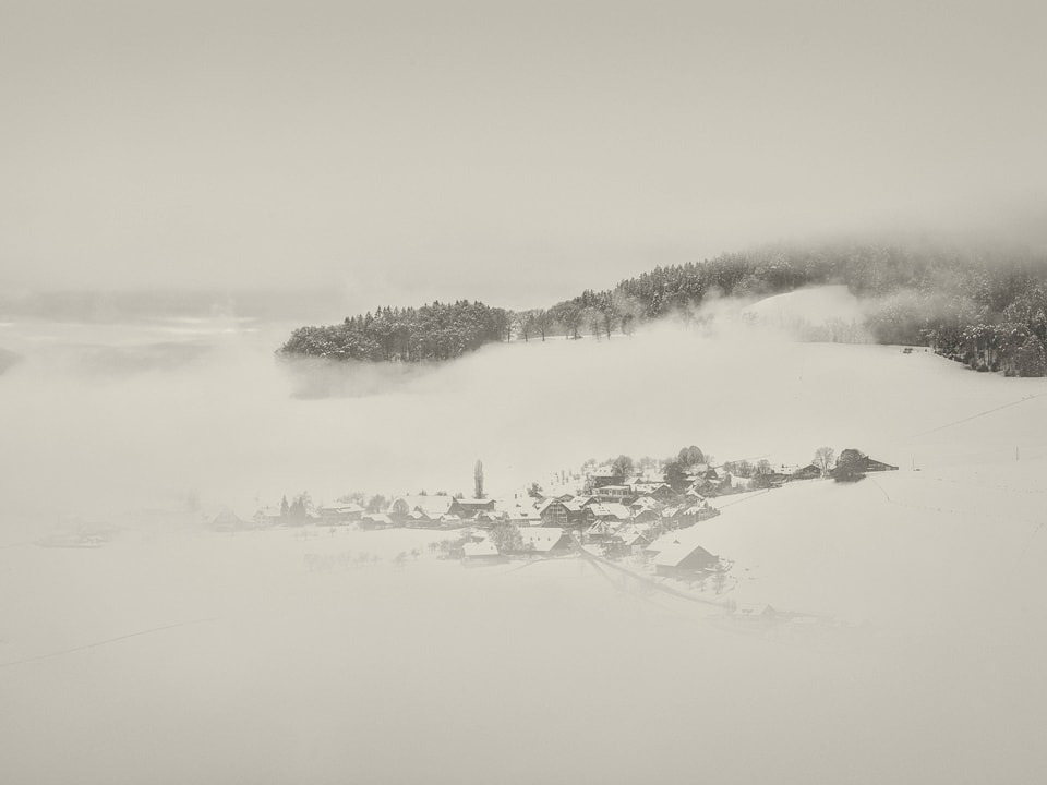 Dorf im Schnee mit Nebelschwaden