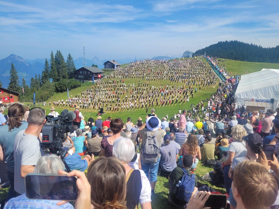 Over a thousand alphorn blowers, watched by a crowd of visitors.