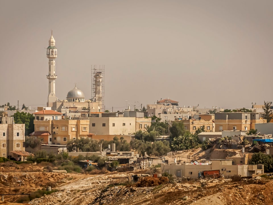 Panoramablick auf eine Stadt mit Moschee und Wohnhäusern.