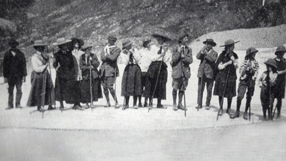 Gruppe von Menschen mit Wanderstöcken vor einem Berg.
