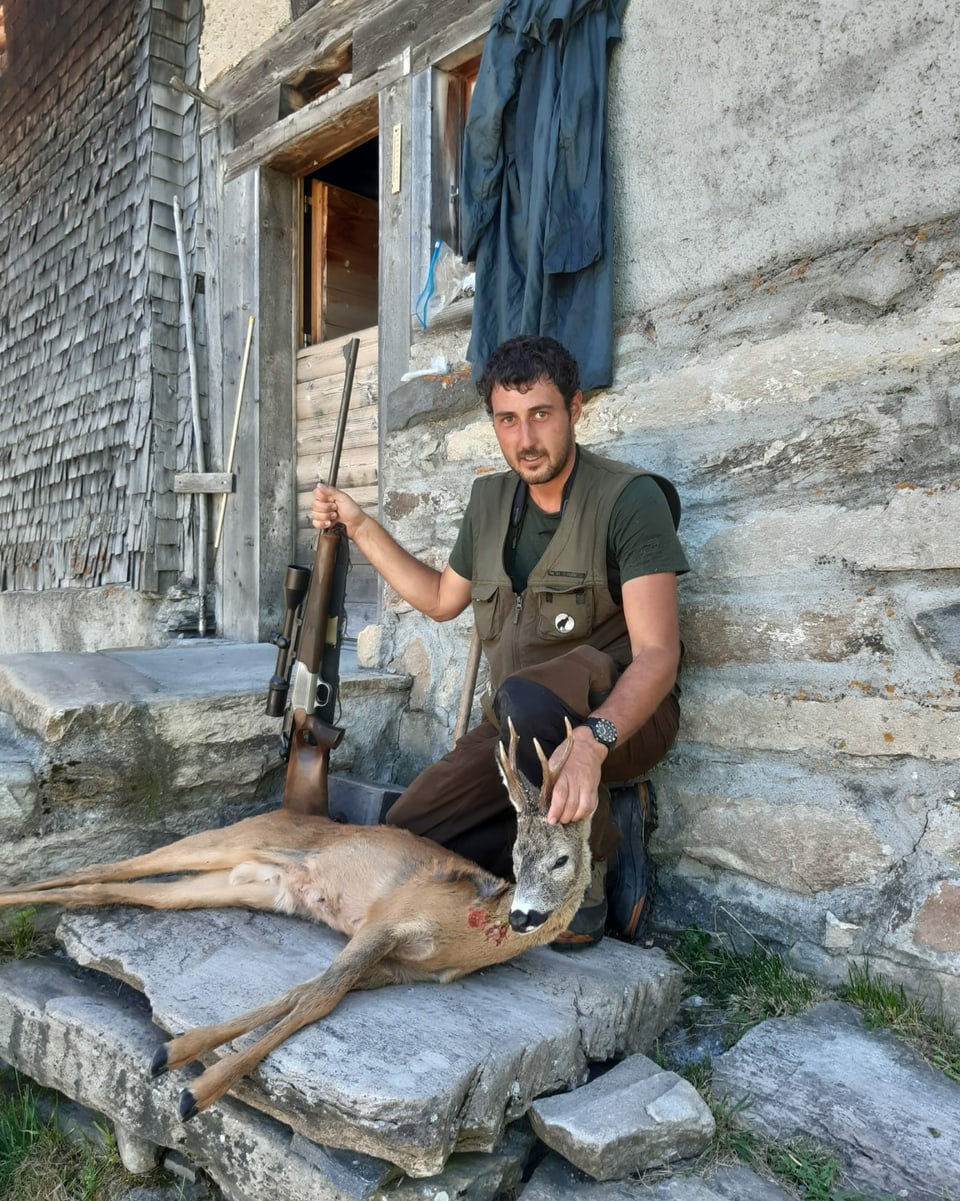 Mann mit Rehbock vor einer Hütte