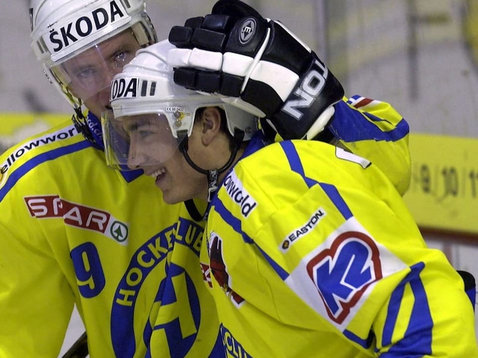 Zwei Eishockeyspieler im gelben Trikot des HC Davos umarmen sich.