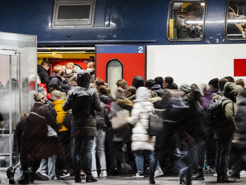 Die Menschenmenge drängt sich am Bahnhof in einen Zug.