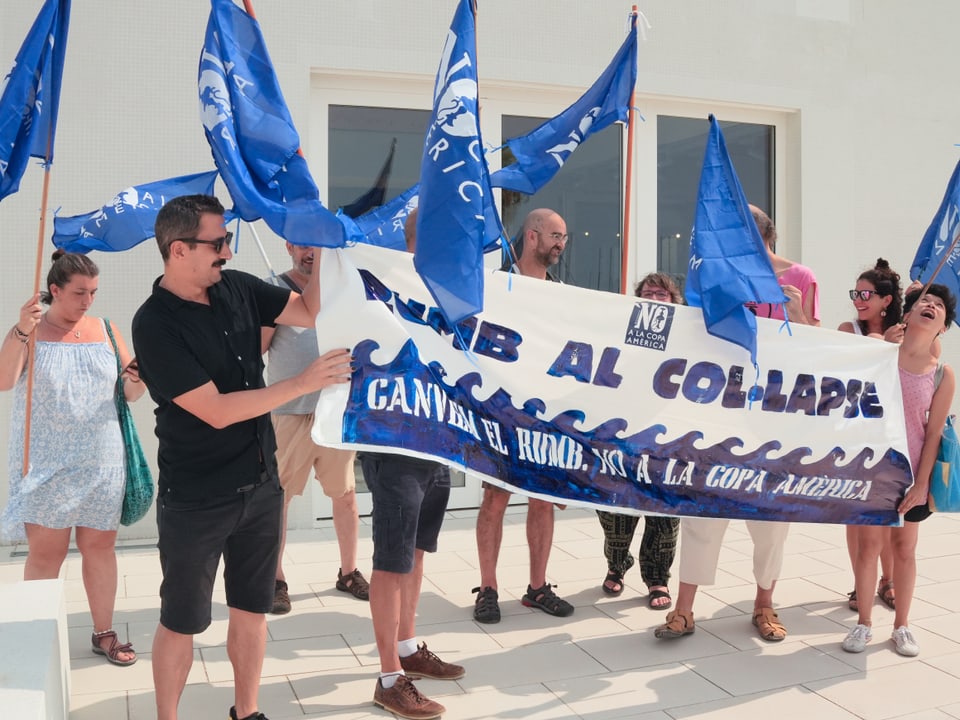 Gruppe von Menschen mit blauen Flaggen und Banner.