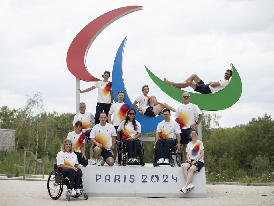 12 Mitglieder der Schweizer Delegation vor dem Agitos Logo in Paris.