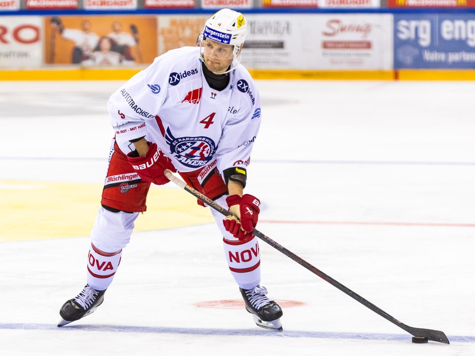 Eishockeyspieler in weiss-rotem Trikot spielt auf dem Eis.