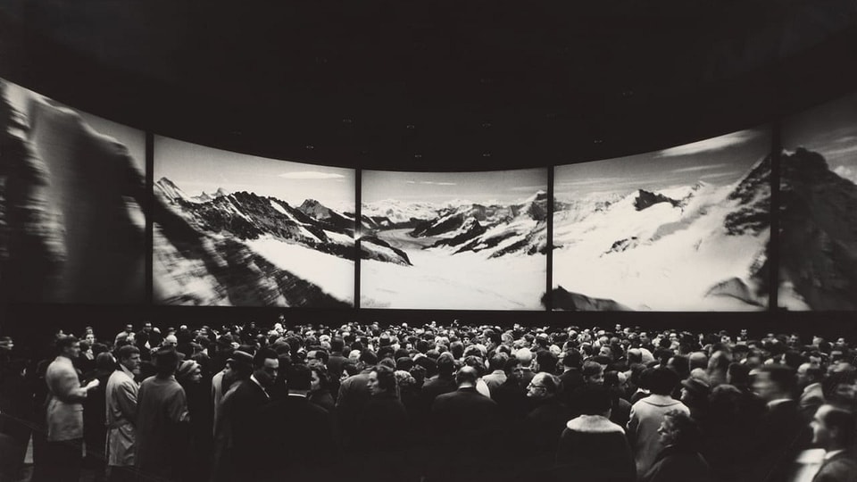 eine schwarz-weiss Fotografie von einem grossen Ausstellungsraum und viel Publikum