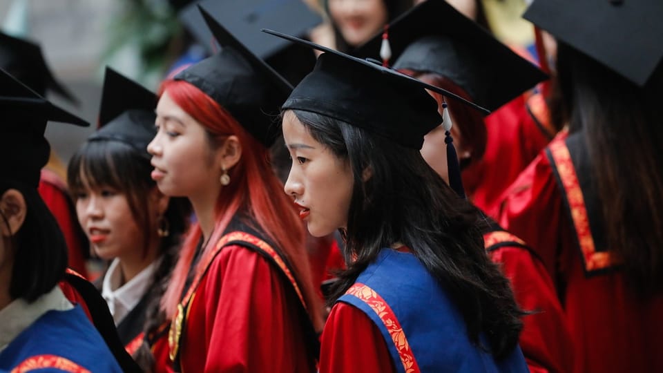 Absolventen in roten Roben und schwarzen Doktorhüten.