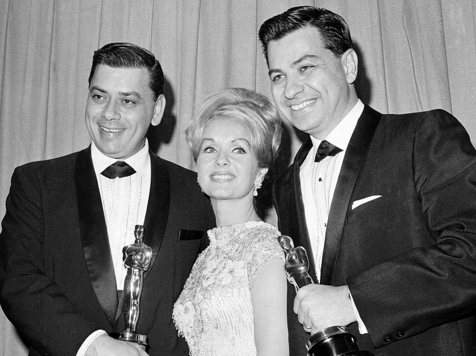 Drei Personen bei einer Preisverleihung halten Oscars.