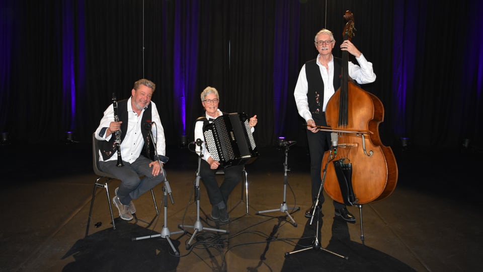 Ländlertrio Jünaiver, Klarinettist, Akkordeonistin und Bassgeigenspieler, alle drei mit weissem Hemd oder Bluse und schwarzer Weste