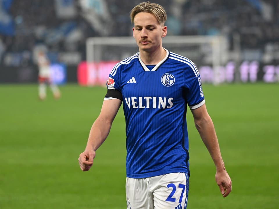 Fussballspieler in blauem Schalke-Trikot auf dem Spielfeld.