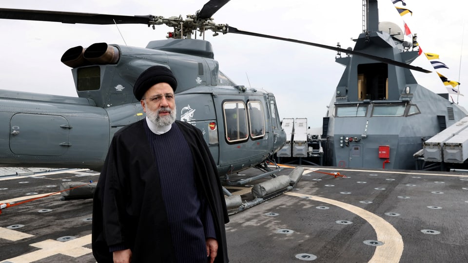Person steht auf einem Militärschiffdeck neben einem Hubschrauber.