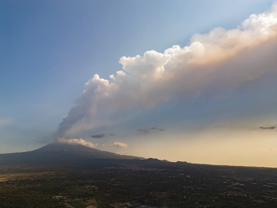 Rauchwolke ausbreitend vom Vulkan über Landschaft.