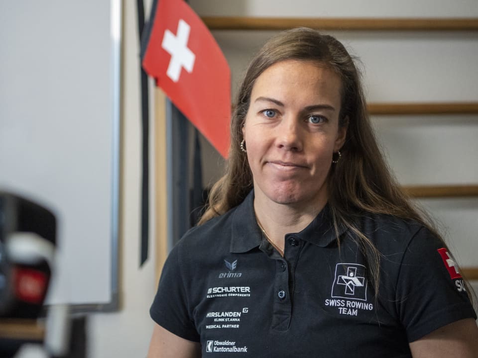 Frau im Swiss Rowing Team-Poloshirt vor Schweizer Flagge.