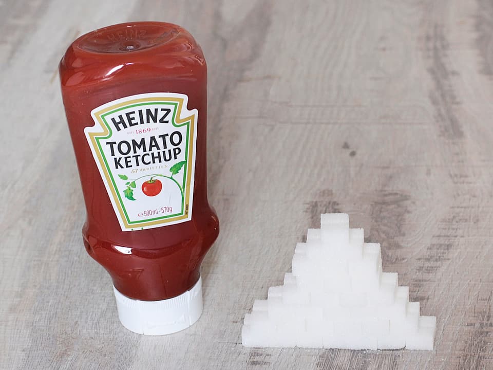 Ketchup-Flasche neben einem Turm Würfelzucker.