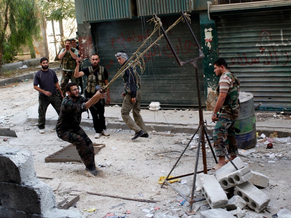 Syrische Aufständische werfen mit einem selbst gebauten Katapult kleine Bomben auf Angehörige der Armee ab.