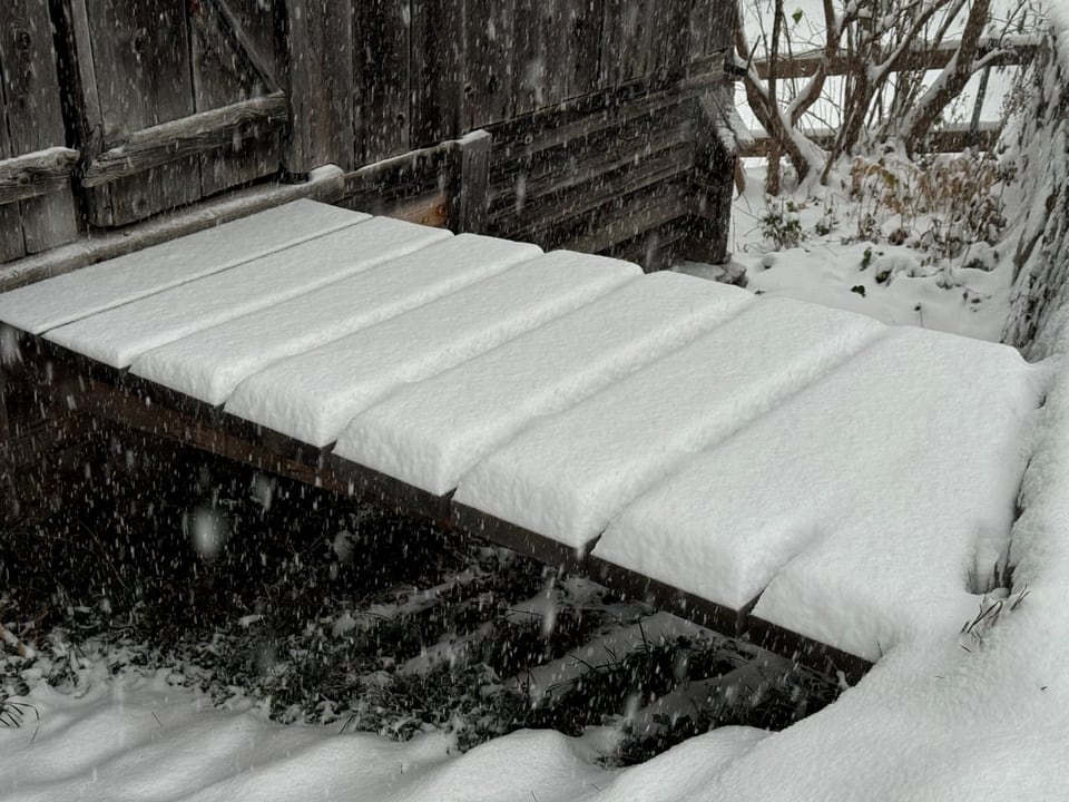 Schneetreppe neben Holzhütte.