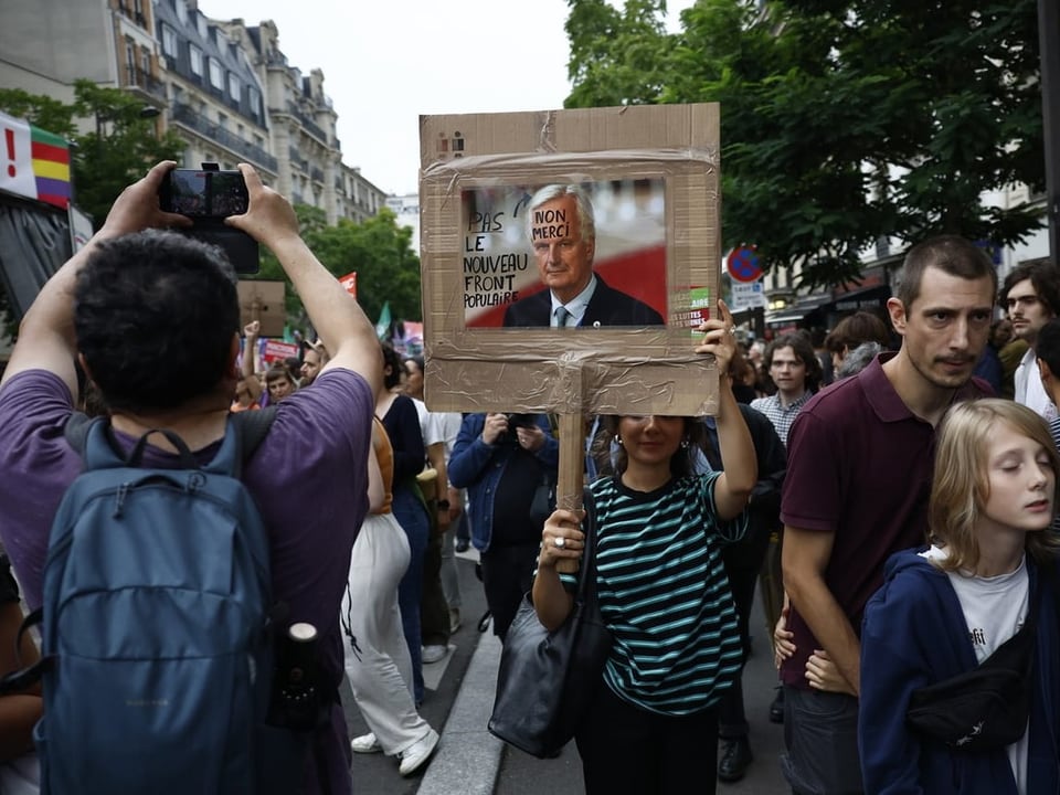 Menschen auf einer Demonstration, darunter eine Person, die ein Plakat mit einem Bild von einem Mann hält.