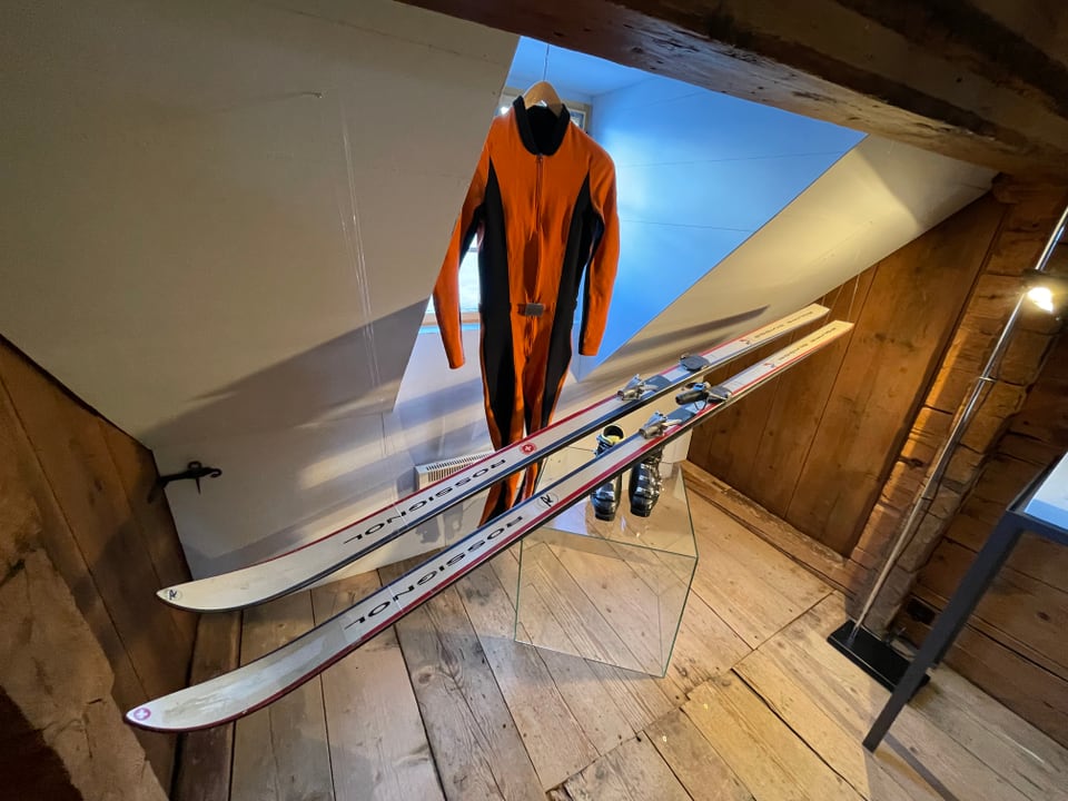 Oranger Skianzug und Ski.