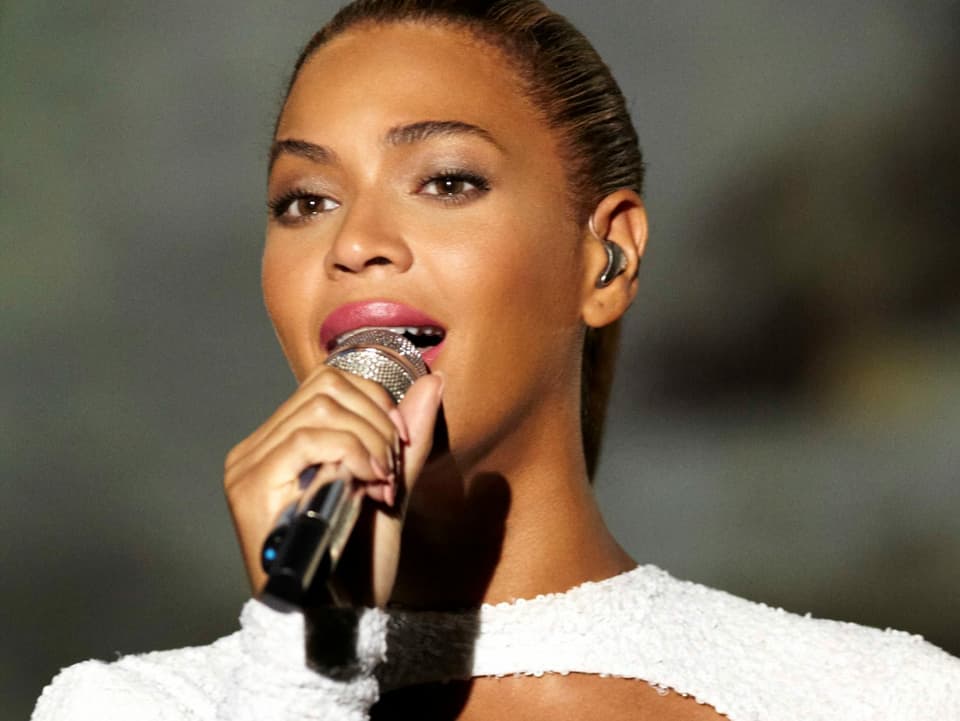 Beyoncé singt auf einer Bühne in ein Mikrofon.