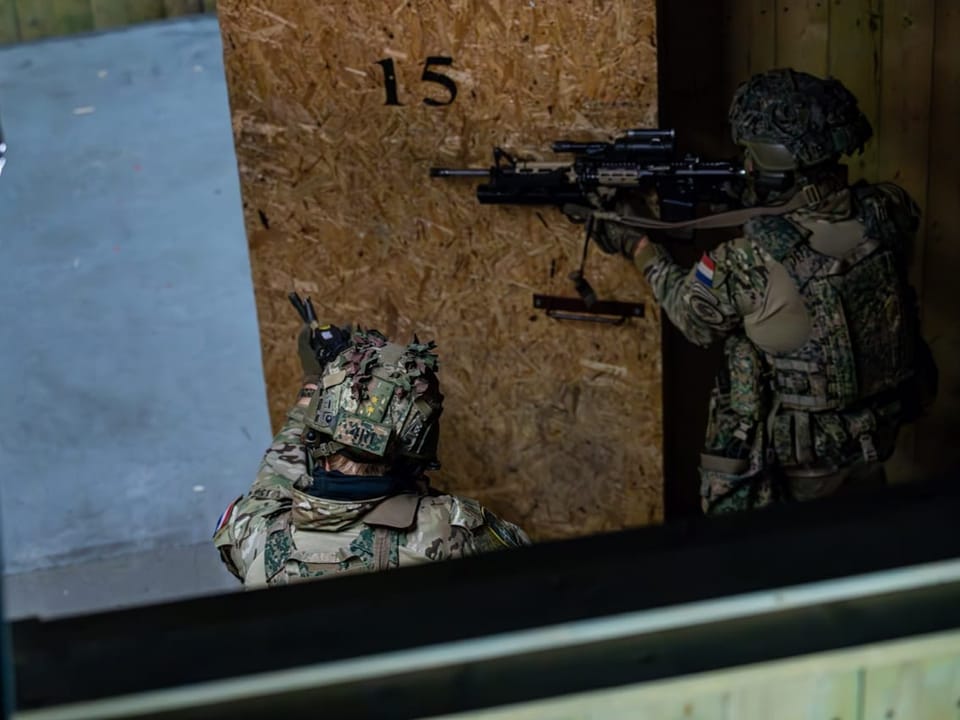 Zwei Soldaten in Tarnkleidung mit Gewehren bei einer Militärübung.