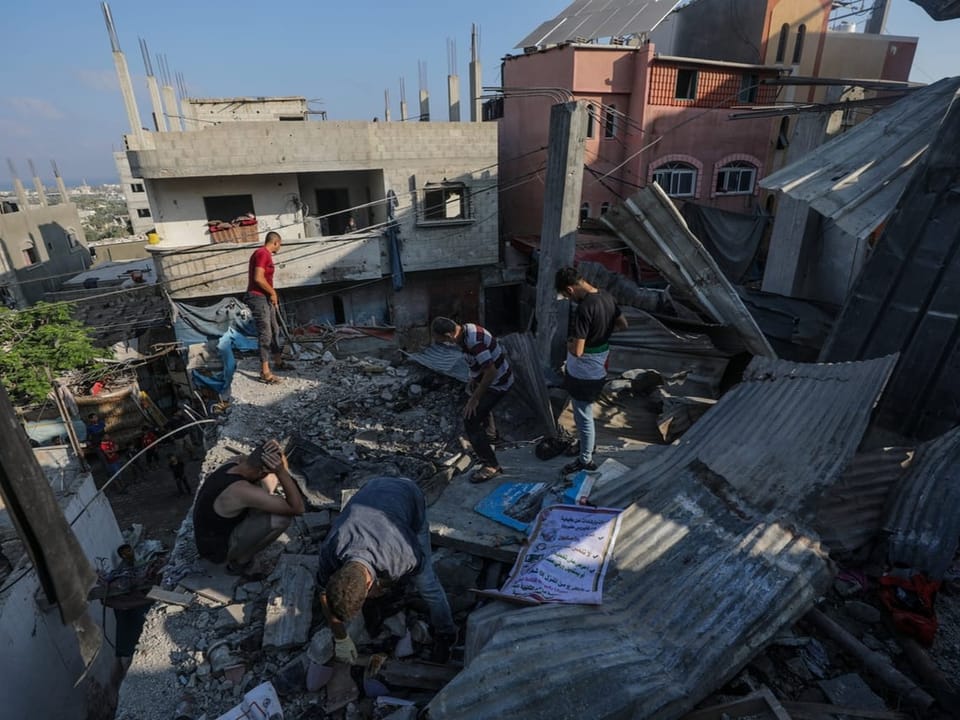 Menschen räumen nach der Zerstörung ein beschädigtes Haus auf.