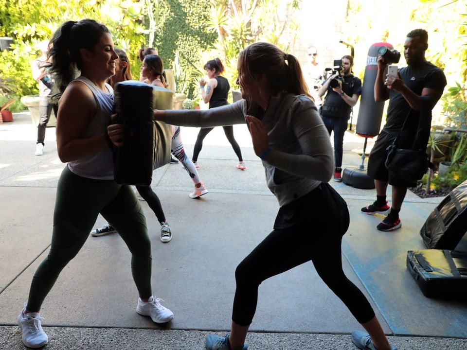 Women train martial arts outdoors.