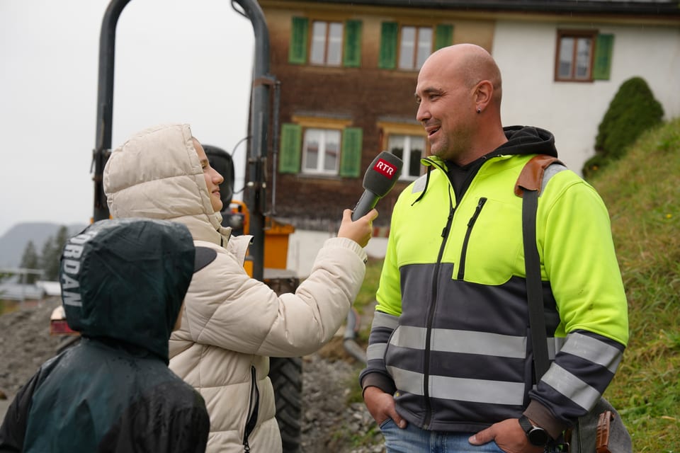 Reporter interviewt einen Bauarbeiter im Freien.