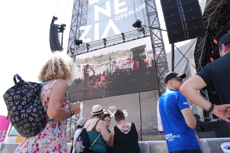 Menschenmenge vor einer Open-Air-Bühne mit grosser Leinwand.