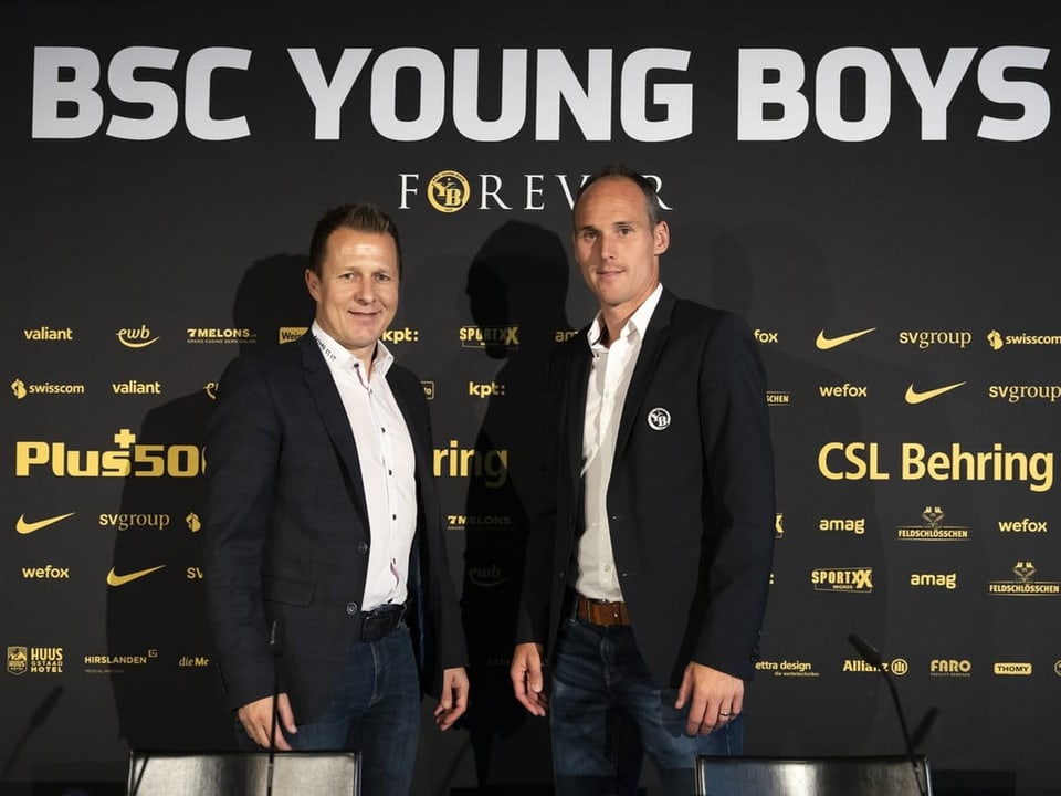 Zwei Männer stehen vor einer Werbewand mit dem Logo des BSC Young Boys.