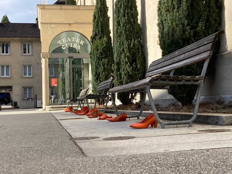 Bancs per seser, calzers oranschs avant ils bancs. davos l'entrada dal teater cuira